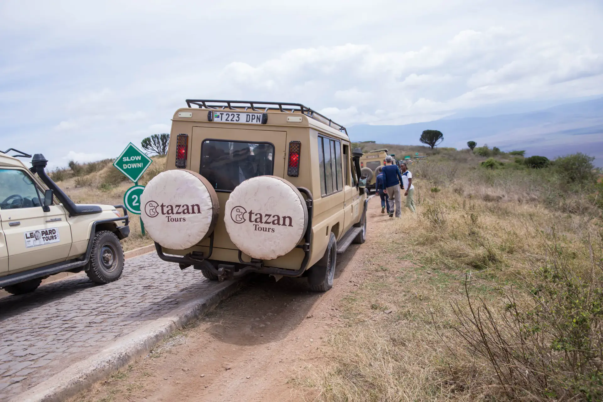 Tazan Tours safari vehicle on the road along the crater rim