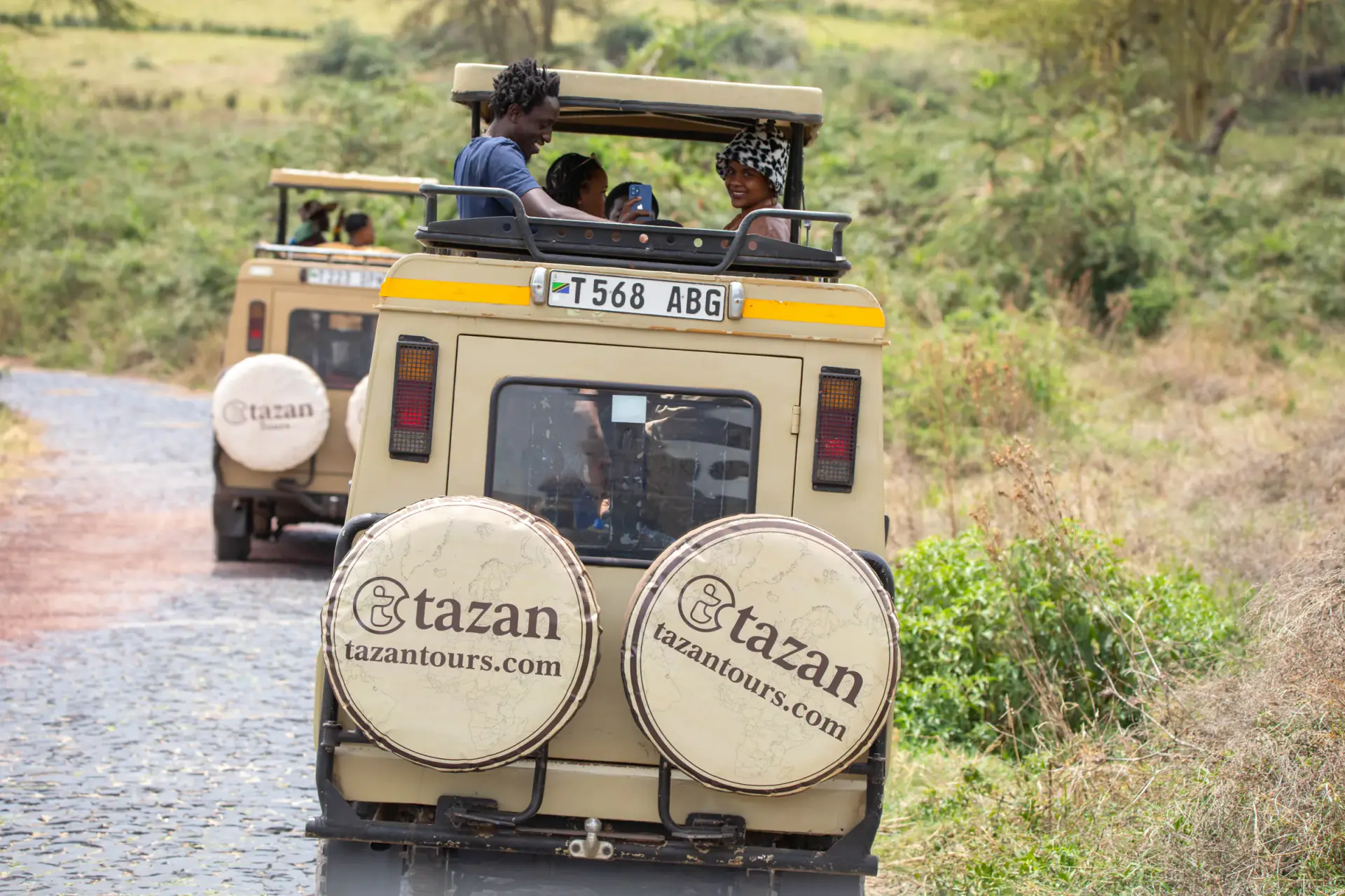 Tazan Tours safari vehicles with pop-up roofs on a forest road