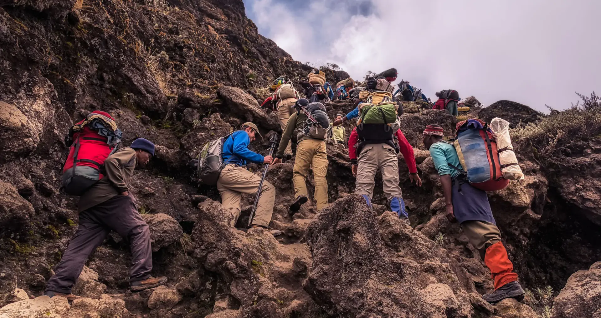Trekkers scrambling up a rocky section of the Barranco Wall