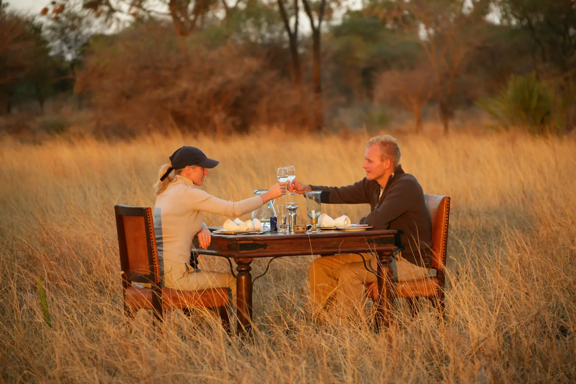 Couple toasting at a private dinner table in golden savanna grass
