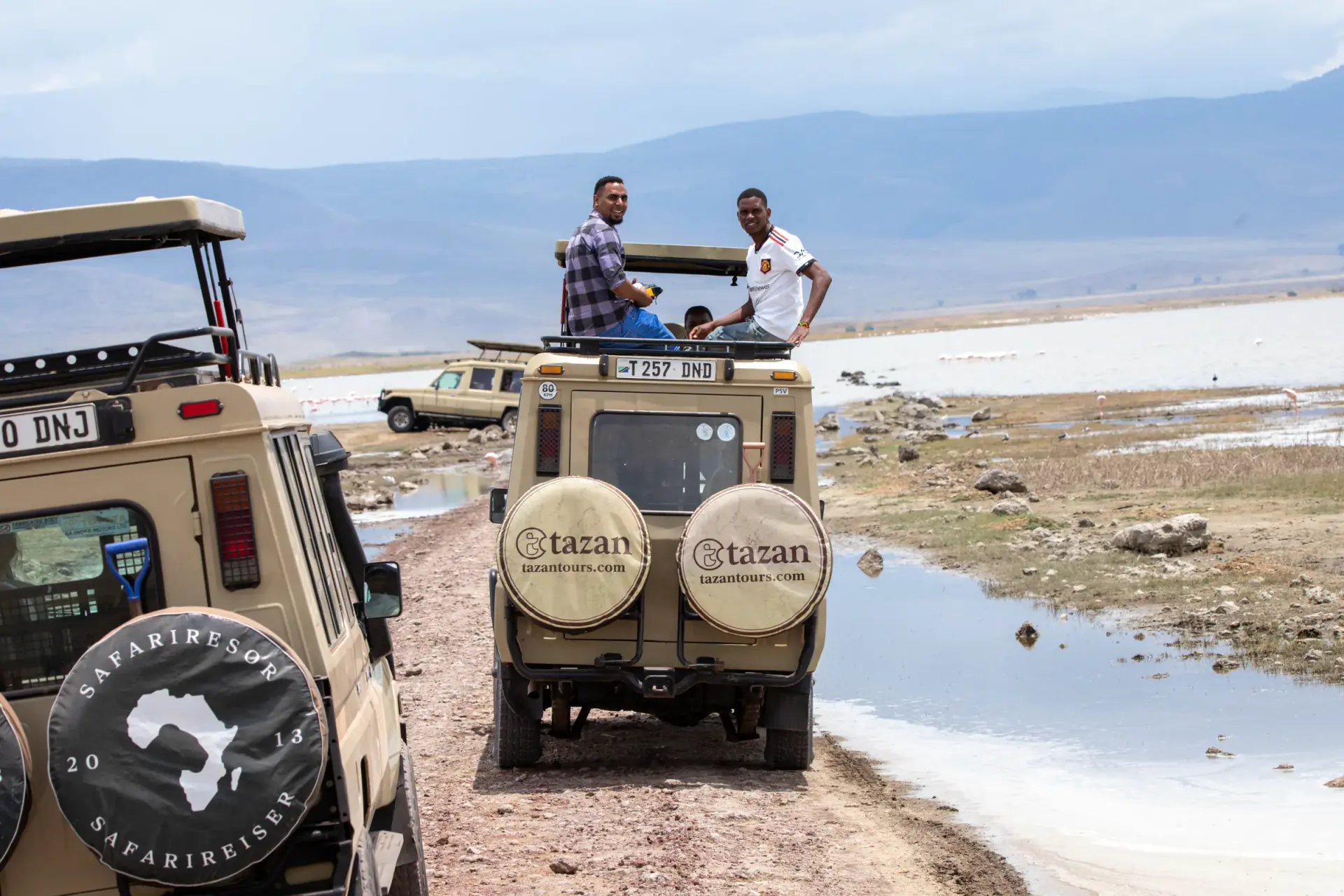 Guests on the roof of a Tazan Tours vehicle by the lake shore