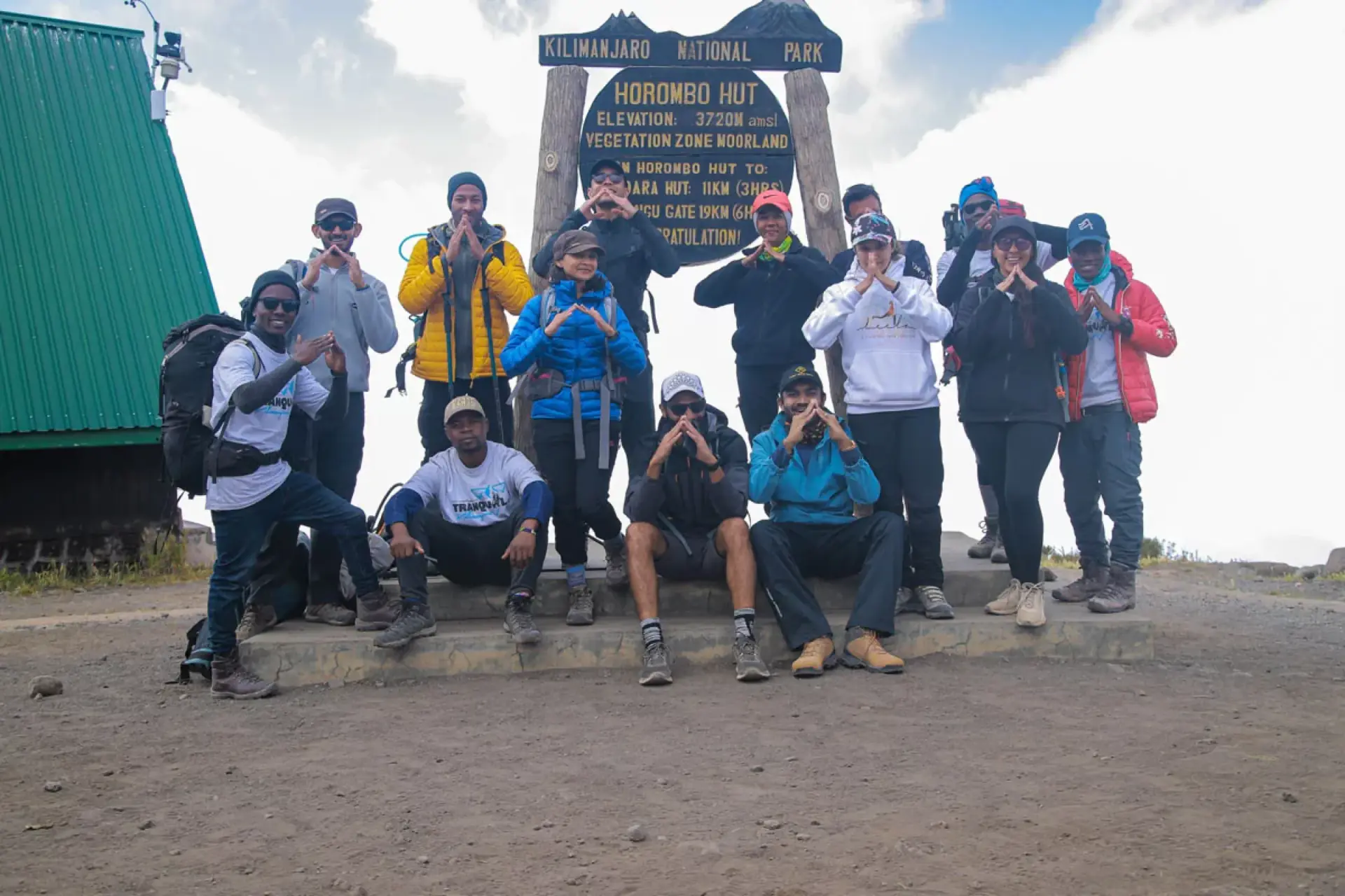 Trekking group posing at the Horombo Hut sign on Kilimanjaro