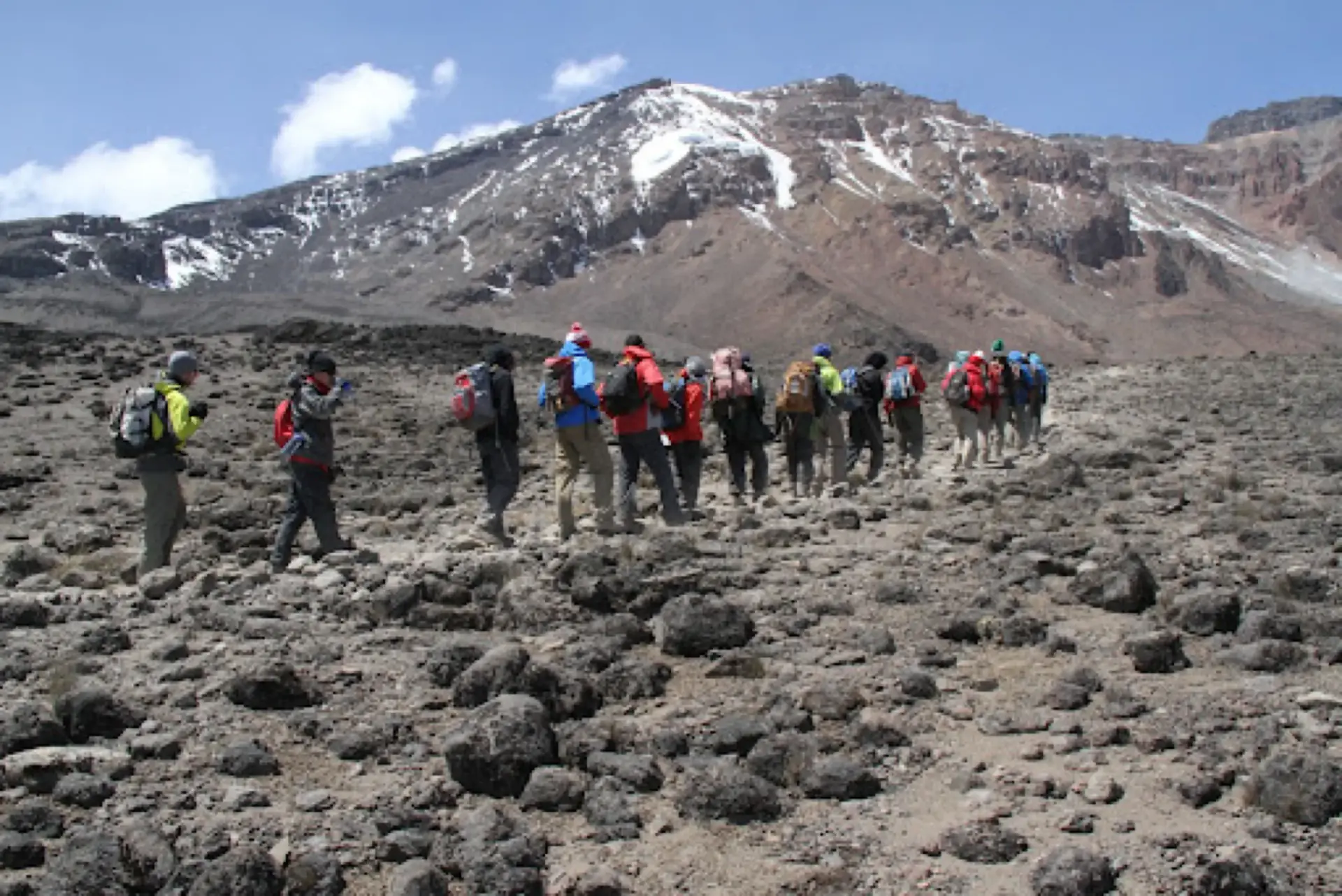 Line of trekkers crossing the rocky saddle toward Kibo