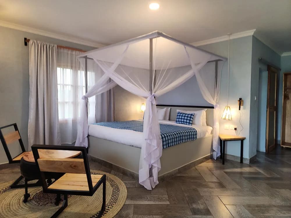 Suite at Heart & Soul Lodge in Karatu with a netted four-poster bed and woven rug