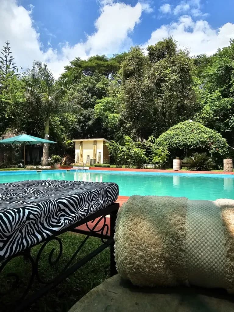 Poolside lounger and rolled towel beside the garden pool at Ilboru Safari Lodge