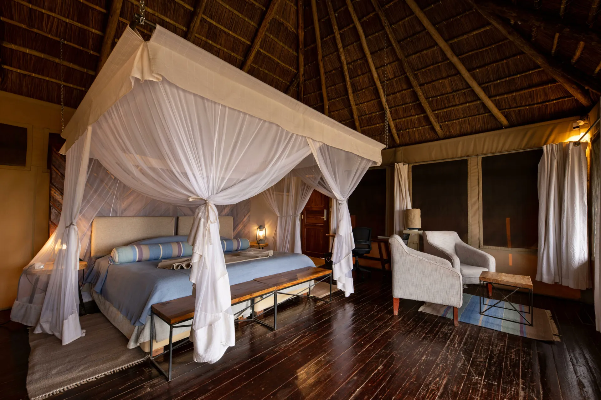 Lamp-lit tented suite at Kubu Kubu with a canopy bed under a high thatched roof