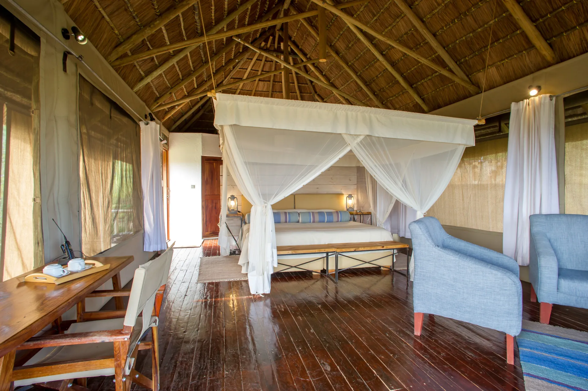 Kubu Kubu suite with armchairs, a writing desk and a netted canopy bed