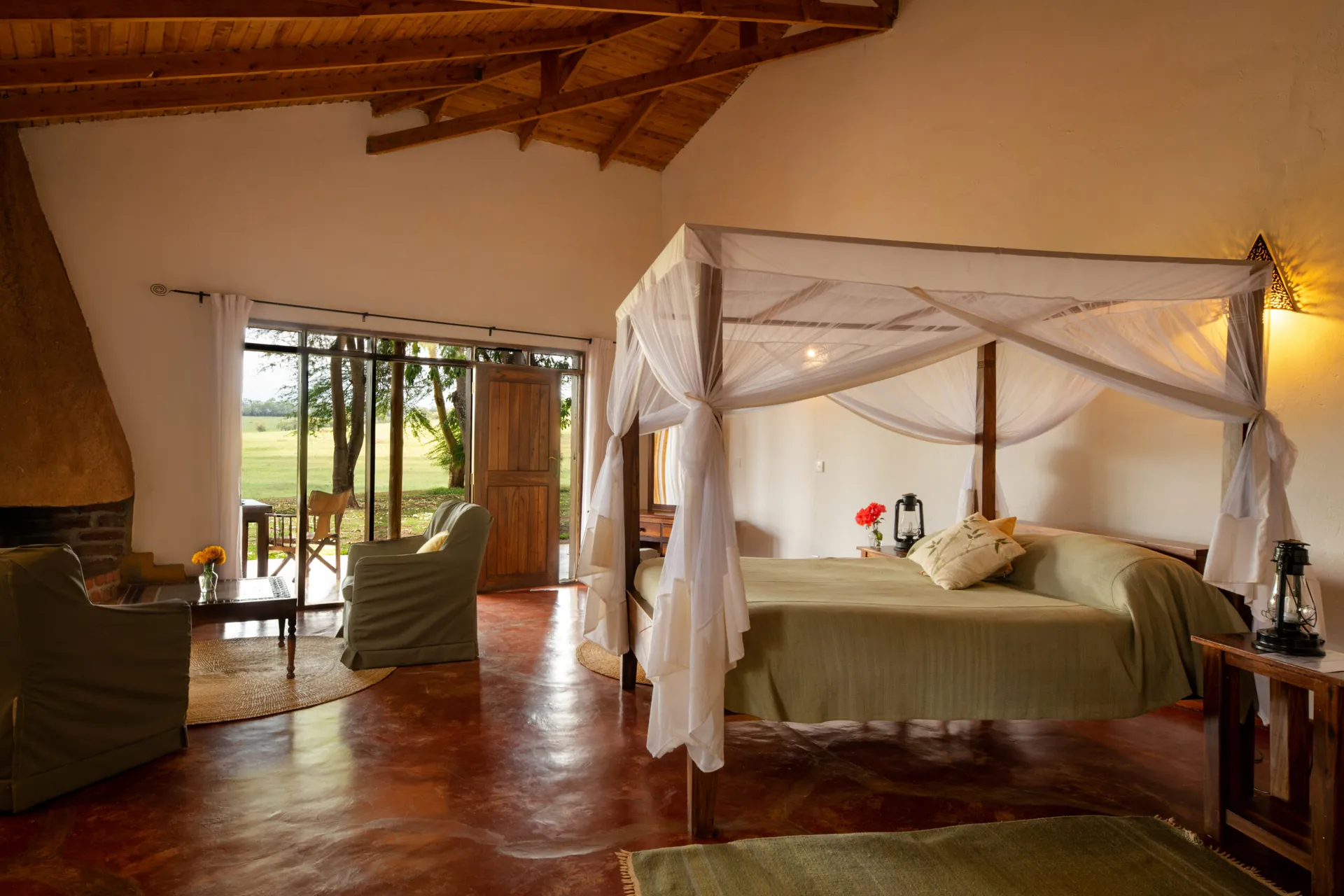 Suite at Ngorongoro Farm House with a four-poster bed, a fireplace and doors open to the lawn