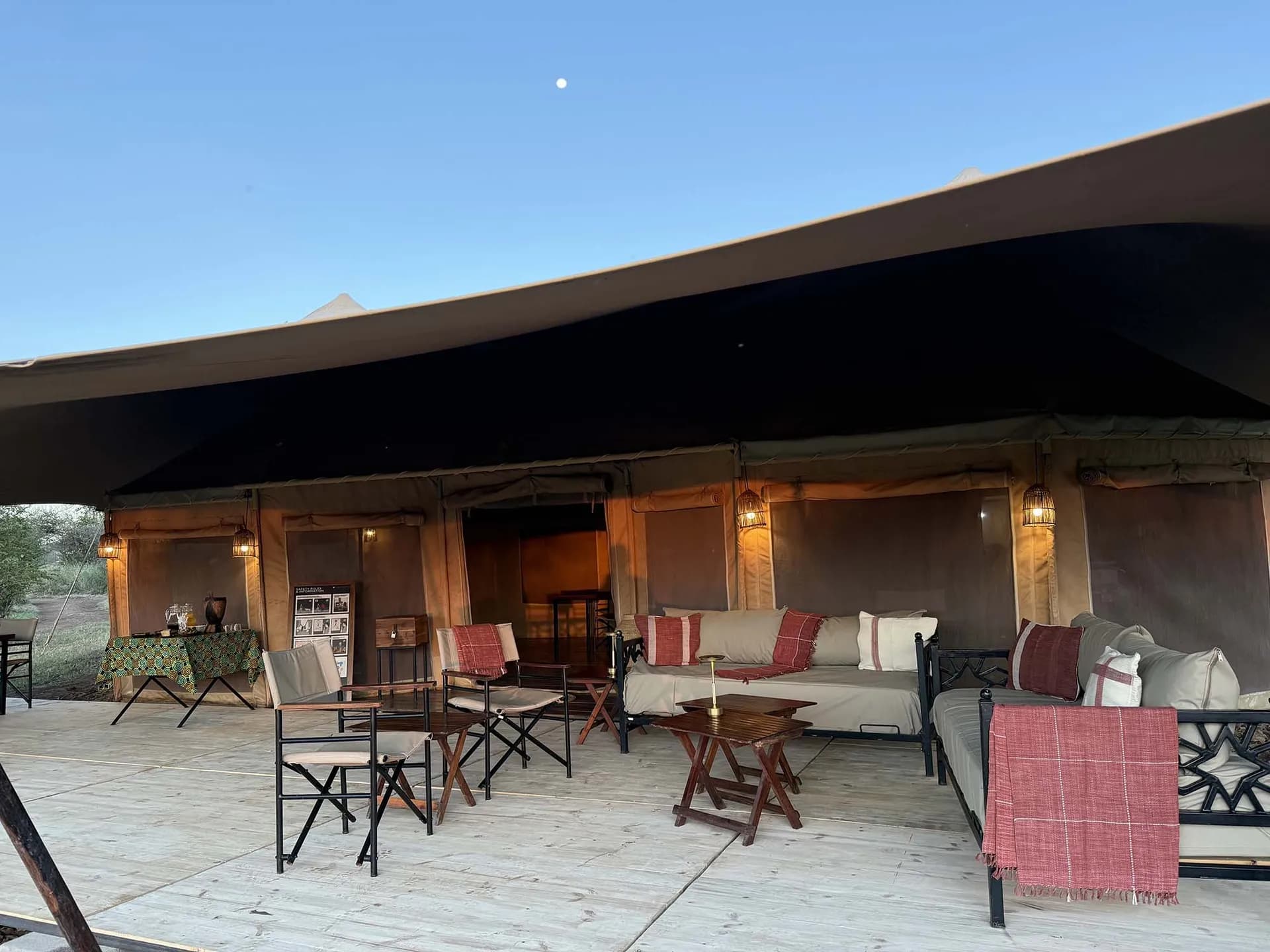 Lounge deck with sofas and director's chairs under the main tent at The Whisper Tarangire