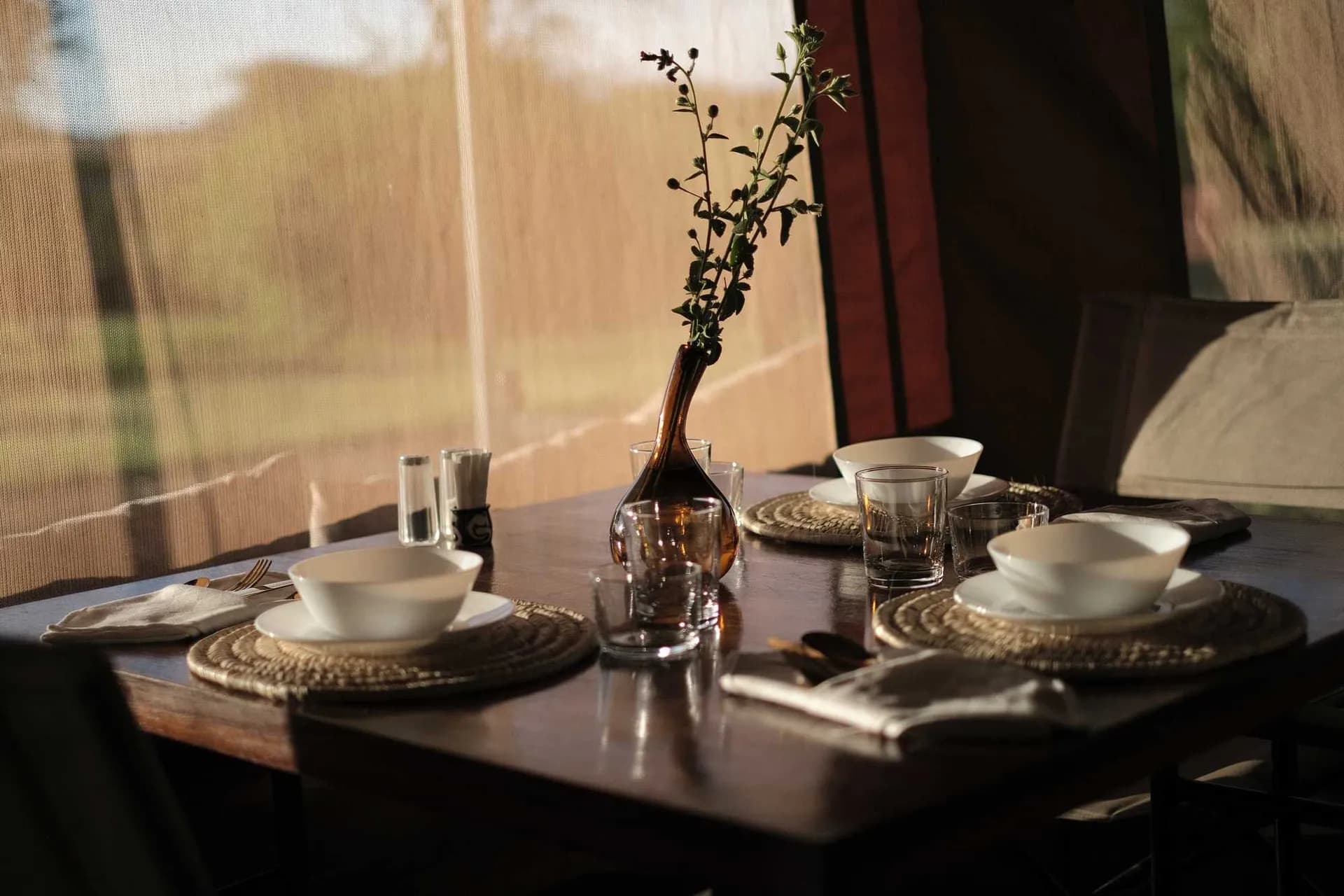 Table laid for a meal in warm light inside the dining tent at The Whisper Tarangire
