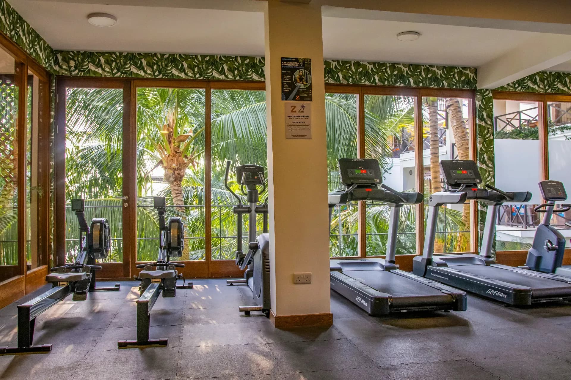 Gym at Z Hotel with treadmills and rowing machines facing palm trees