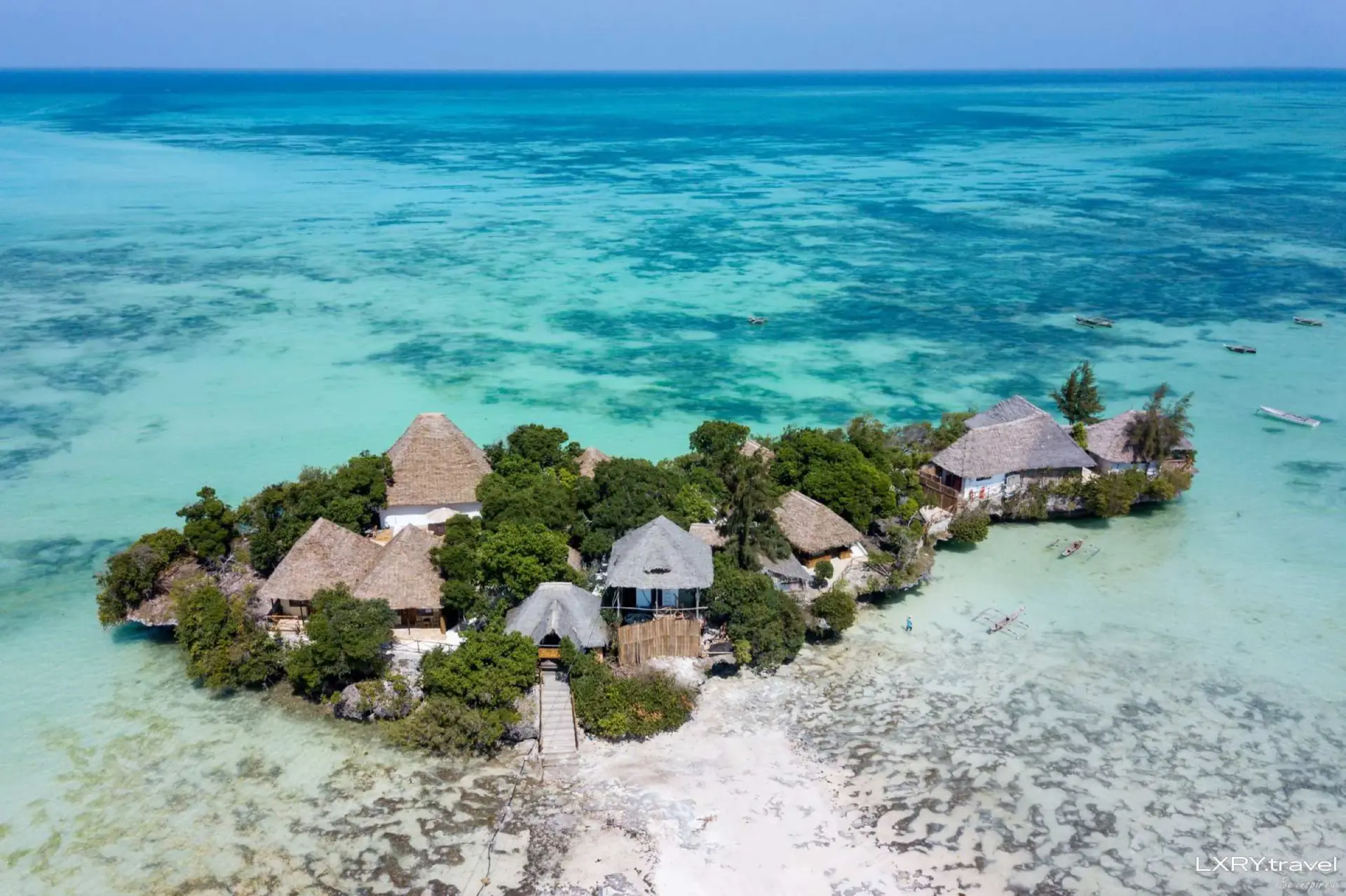 Aerial view of a rocky islet with thatched buildings in the Zanzibar lagoon