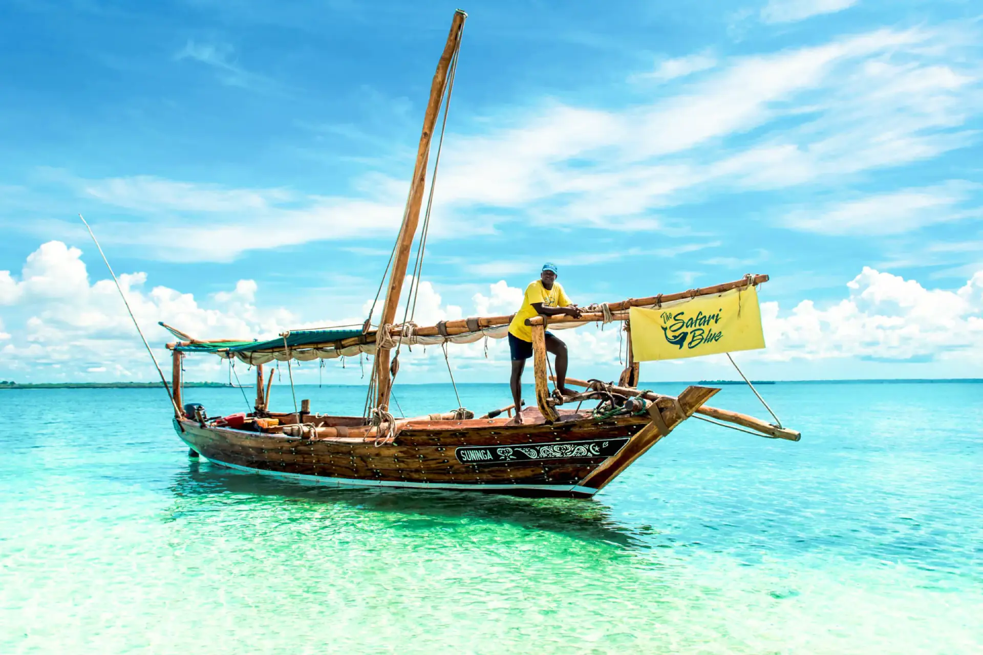 Traditional dhow sailing boat in clear turquoise water off Zanzibar